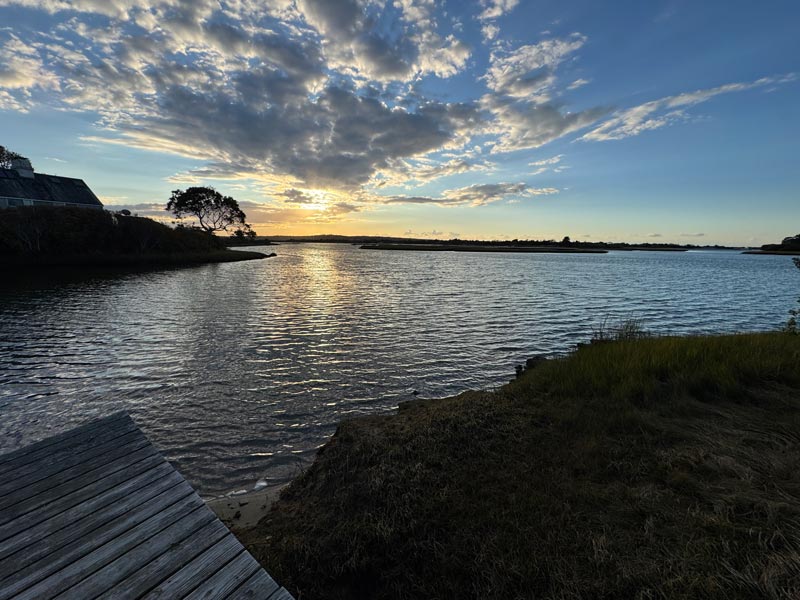 Sunset over a tranquil lake with soft clouds and a radiant sky