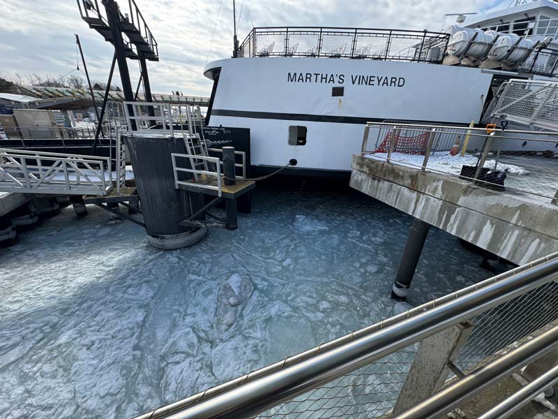 Ferry docked at a pier with frozen water surrounding the landing area.