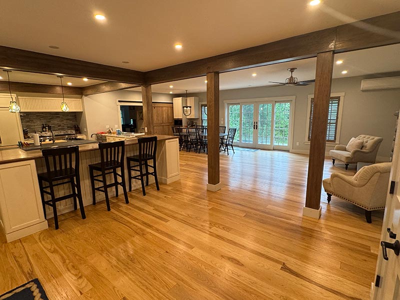 open-concept kitchen and dining area with wooden floors and beams