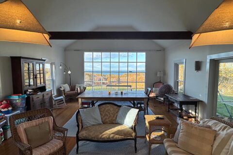 A cozy living room with large windows showing a scenic autumn view
