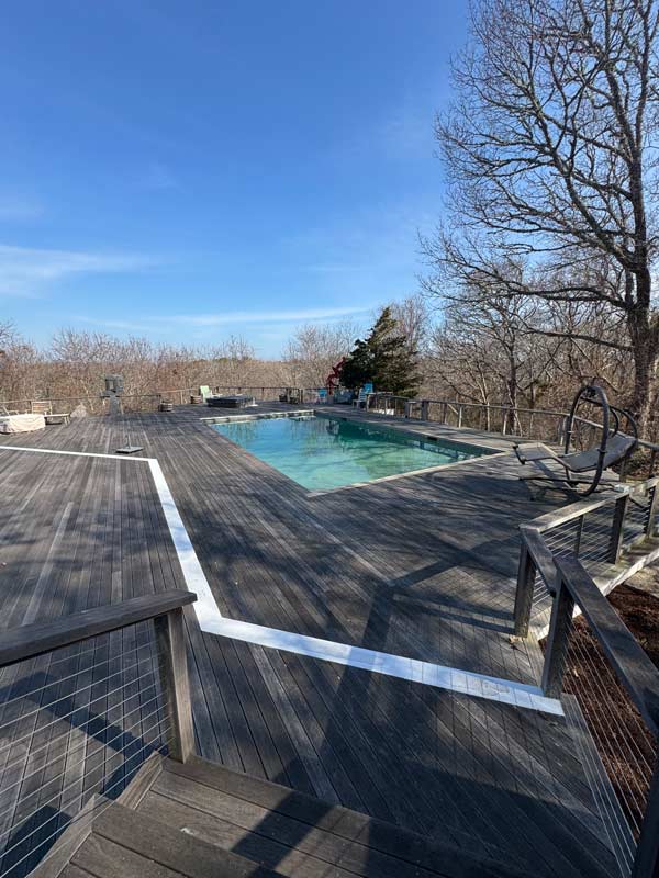 Outdoor pool on a wooden deck surrounded by trees 