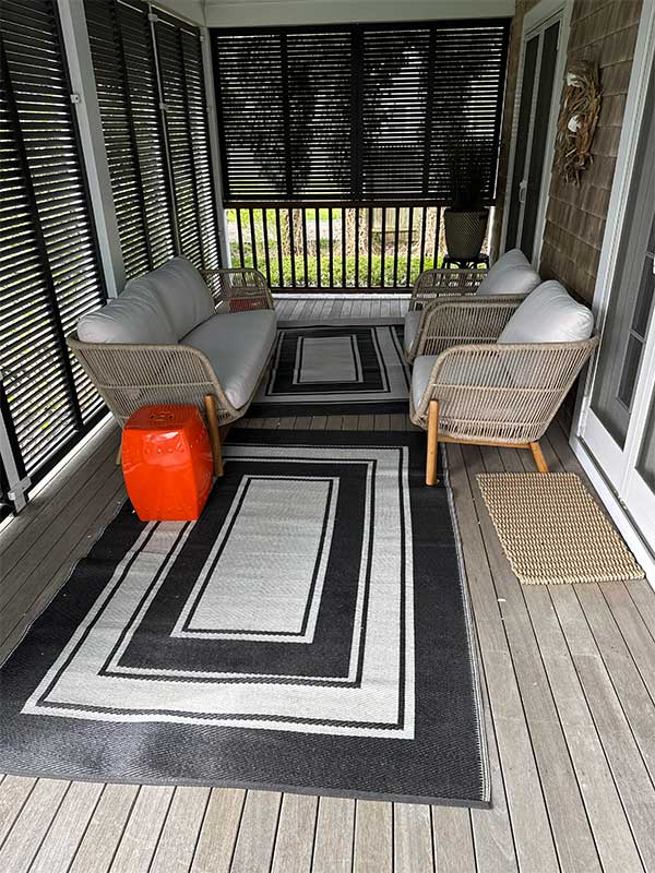 Covered porch with two chairs, sofa, and rug